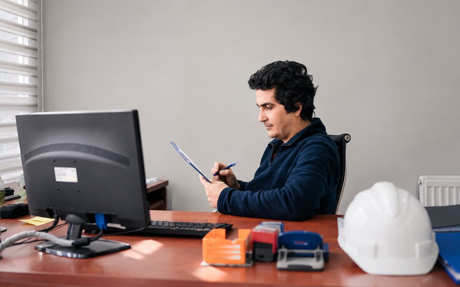 Electrical inspector reviewing permit paperwork at his desk